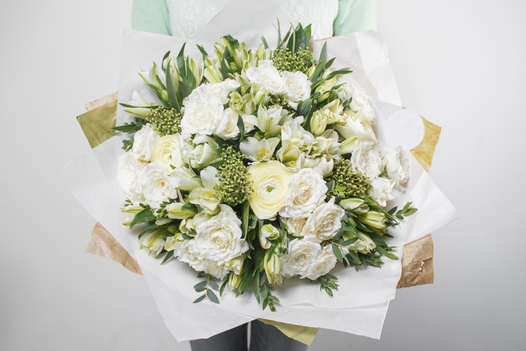 rich bouquet flowers of different colors mixed in woman hand .